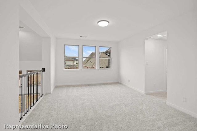 carpeted spare room featuring baseboards and visible vents