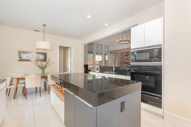 kitchen with white cabinetry, built in microwave, light tile patterned floors, and oven