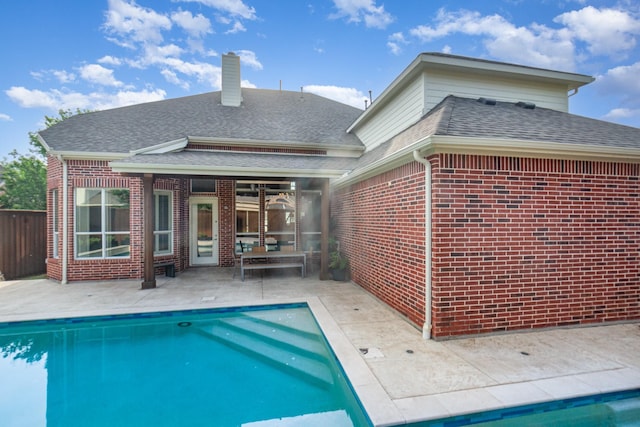 back of house with roof with shingles, a fenced in pool, a patio area, and brick siding
