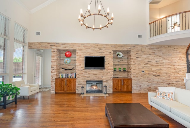living area with a high ceiling, a fireplace, wood finished floors, and visible vents