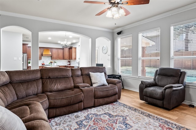 living room featuring light wood-style floors, arched walkways, ceiling fan with notable chandelier, and a healthy amount of sunlight