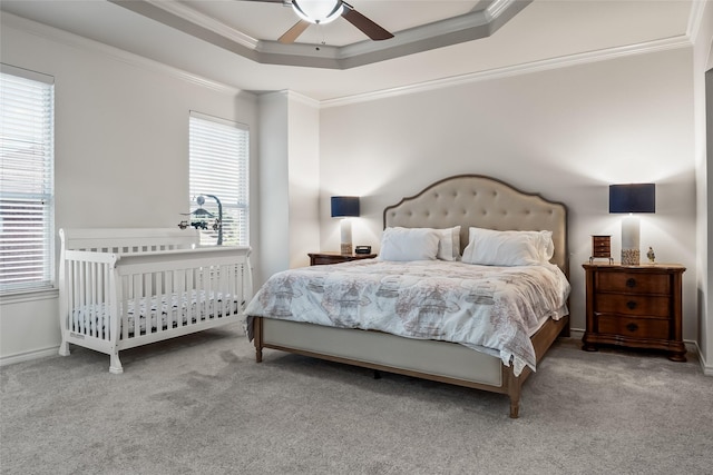 bedroom with ceiling fan, carpet floors, baseboards, ornamental molding, and a tray ceiling