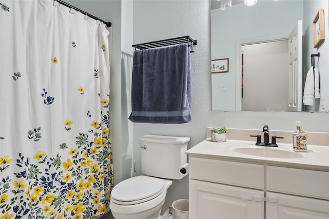 full bath featuring vanity, a textured wall, a shower with shower curtain, and toilet