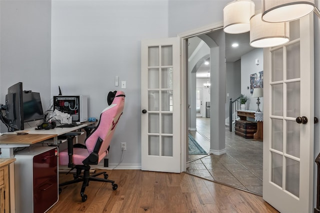 home office featuring arched walkways, baseboards, french doors, and wood finished floors