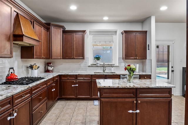 kitchen featuring decorative backsplash, custom exhaust hood, gas cooktop, a sink, and light tile patterned floors