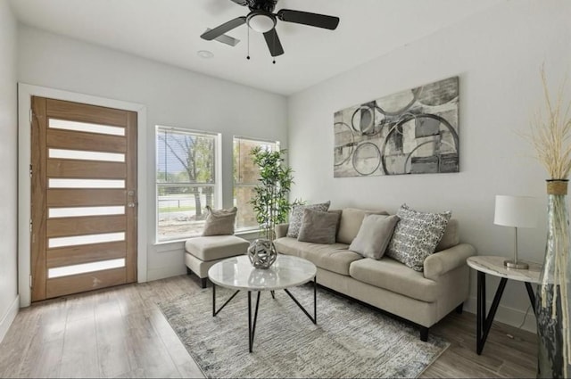 living area featuring a ceiling fan, baseboards, and wood finished floors