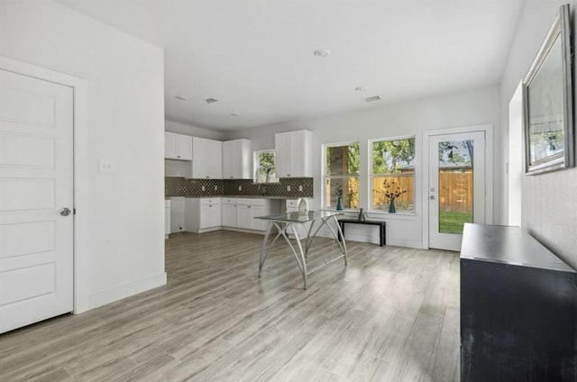 kitchen featuring baseboards, light wood-style flooring, white cabinetry, and tasteful backsplash