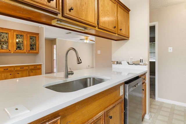 kitchen featuring brown cabinetry, light floors, light countertops, a sink, and dishwasher