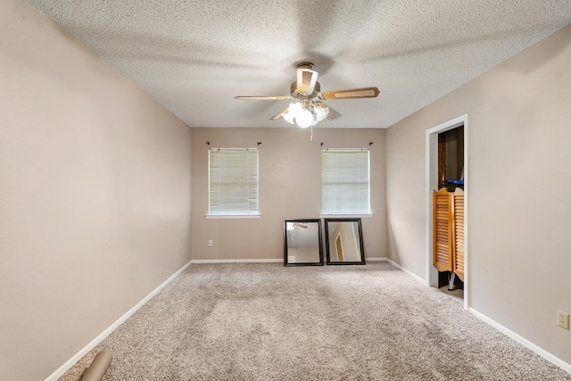 carpeted empty room with baseboards, ceiling fan, and a textured ceiling