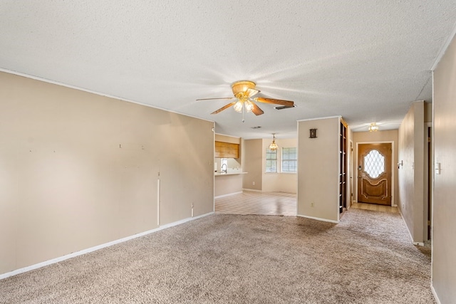 unfurnished living room with carpet floors, ceiling fan, baseboards, and a textured ceiling