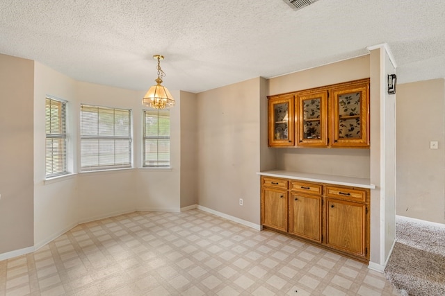 unfurnished dining area featuring baseboards, a textured ceiling, light floors, and a notable chandelier