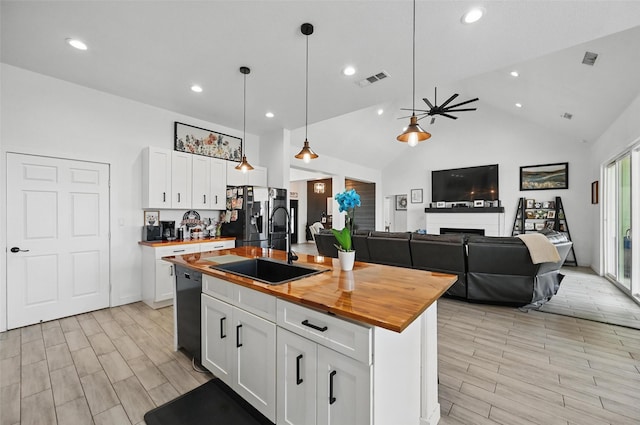 kitchen featuring white cabinets, a sink, butcher block countertops, black dishwasher, and stainless steel refrigerator with ice dispenser