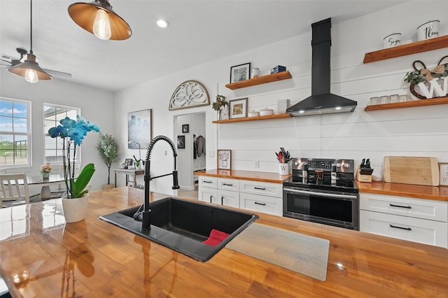 kitchen featuring open shelves, a sink, wall chimney exhaust hood, electric stove, and butcher block counters