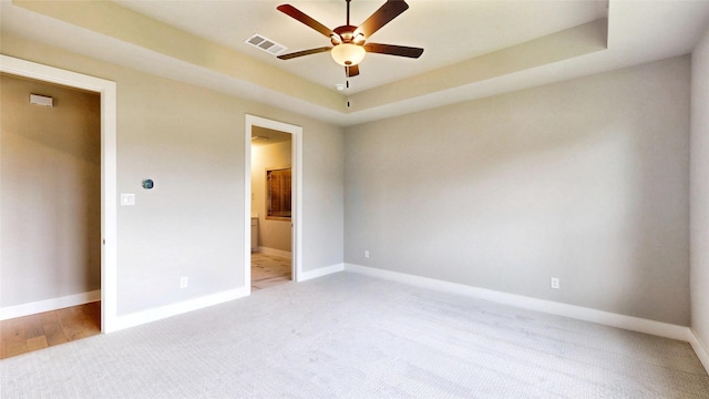 unfurnished bedroom with baseboards, ensuite bathroom, light colored carpet, and visible vents