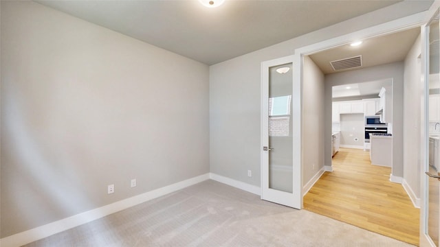 empty room with baseboards, light colored carpet, and visible vents