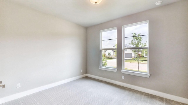 empty room featuring baseboards, plenty of natural light, and light carpet