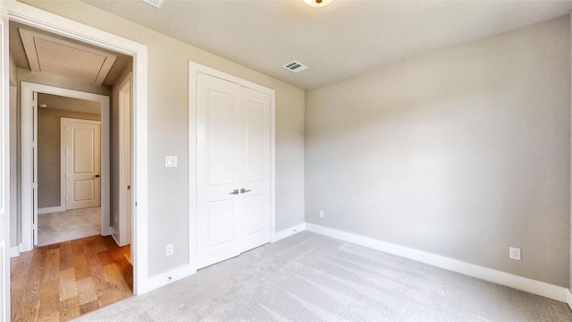 unfurnished bedroom with visible vents, attic access, baseboards, and a closet