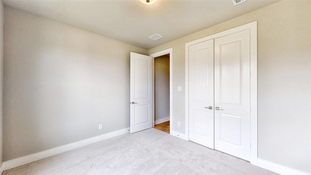 unfurnished bedroom featuring baseboards, carpet, visible vents, and a closet