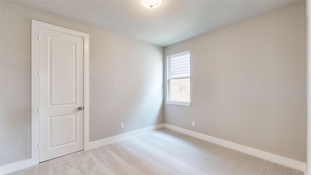 unfurnished room with light colored carpet and baseboards