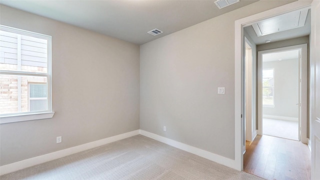 unfurnished room featuring visible vents, a healthy amount of sunlight, and attic access