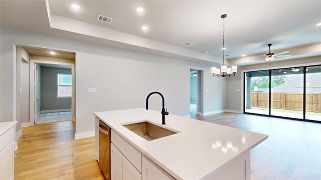 kitchen with a sink, light countertops, stainless steel dishwasher, and light wood-style floors