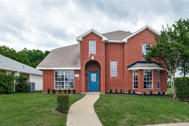 traditional-style house featuring brick siding, a front yard, and roof with shingles