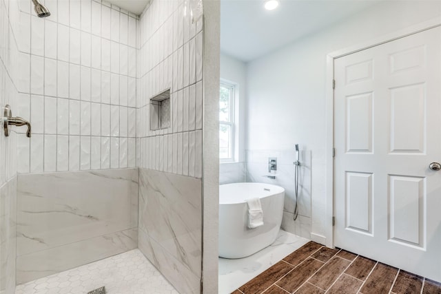 full bathroom with a soaking tub, wood finish floors, and tiled shower