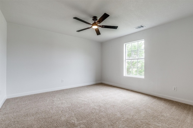 carpeted empty room with visible vents, baseboards, and ceiling fan