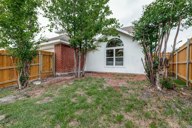 back of property with a fenced backyard, a shingled roof, and brick siding