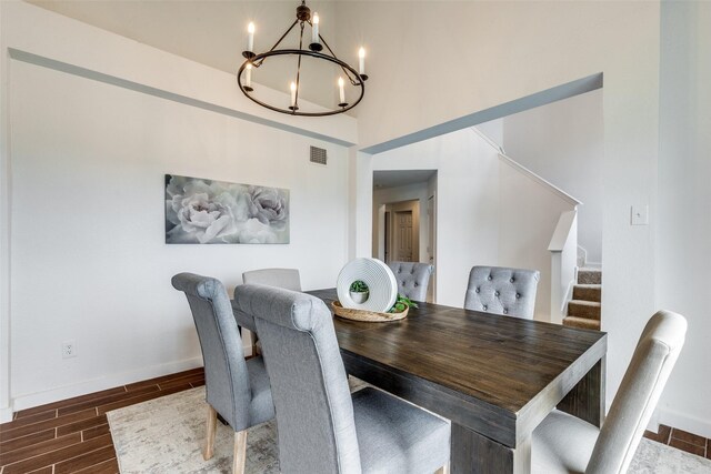 dining room featuring visible vents, wood finish floors, stairway, baseboards, and an inviting chandelier