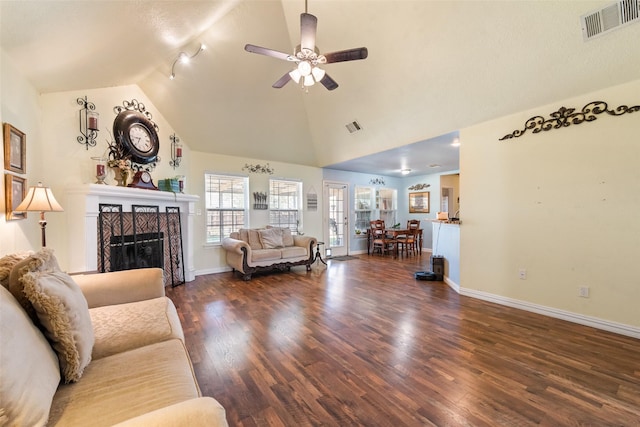 living room with a ceiling fan, a tiled fireplace, dark wood finished floors, baseboards, and lofted ceiling