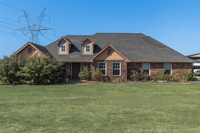 view of front of home featuring brick siding, a shingled roof, and a front lawn