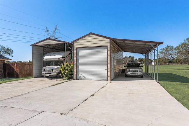 garage featuring a detached carport, fence, and driveway