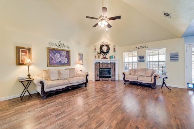 living room featuring visible vents, wood finished floors, ceiling fan, high vaulted ceiling, and a tiled fireplace