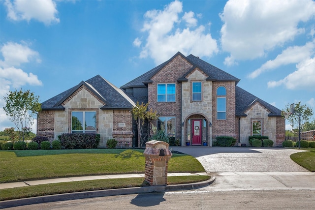 view of front of home featuring brick siding, a front yard, curved driveway, and stone siding