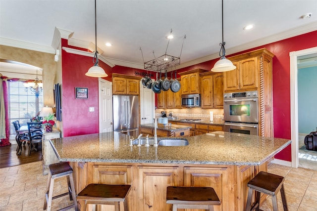 kitchen featuring a large island, a sink, appliances with stainless steel finishes, and ornamental molding