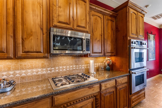 kitchen featuring decorative backsplash, brown cabinetry, stainless steel appliances, and visible vents