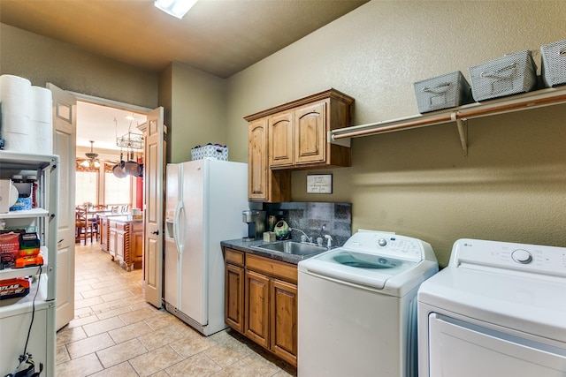 washroom with a textured wall, washing machine and dryer, a sink, cabinet space, and light tile patterned floors