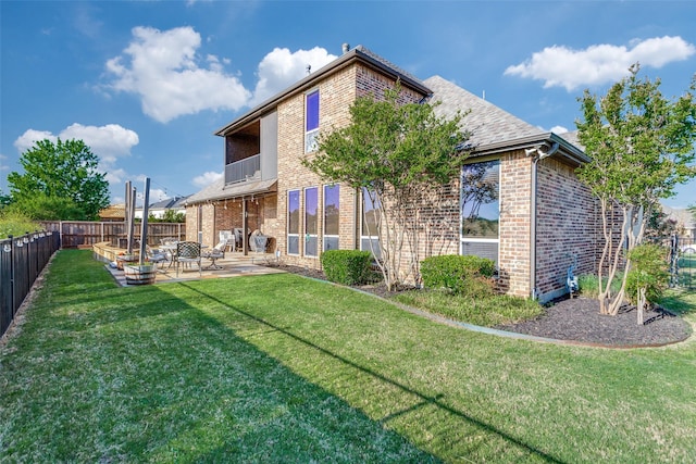 rear view of property featuring brick siding, a fenced backyard, and a patio area