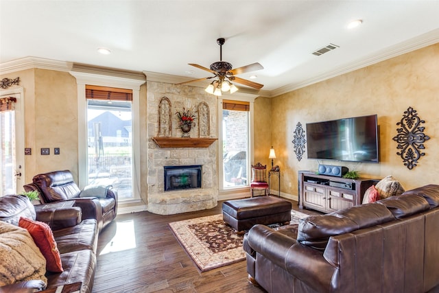 living area with crown molding, a wealth of natural light, ceiling fan, and visible vents