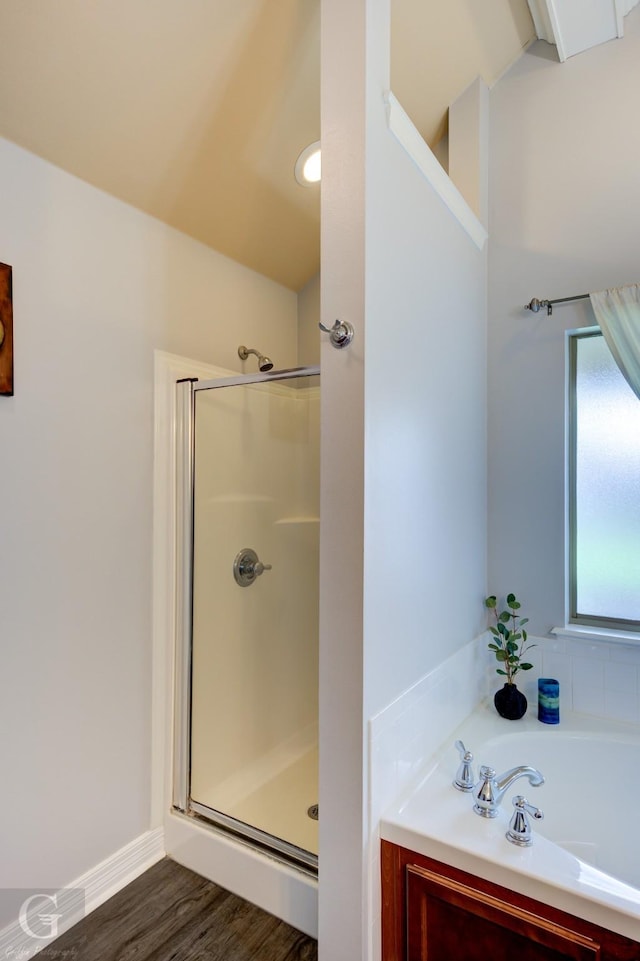 bathroom with a bath, a shower stall, and wood finished floors