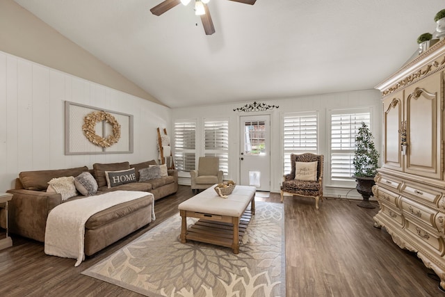 living area featuring ceiling fan, a decorative wall, dark wood-style flooring, and lofted ceiling