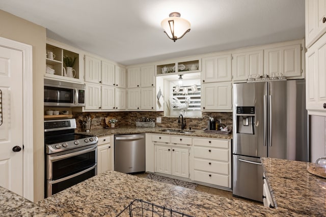 kitchen featuring a sink, appliances with stainless steel finishes, decorative backsplash, and light stone counters