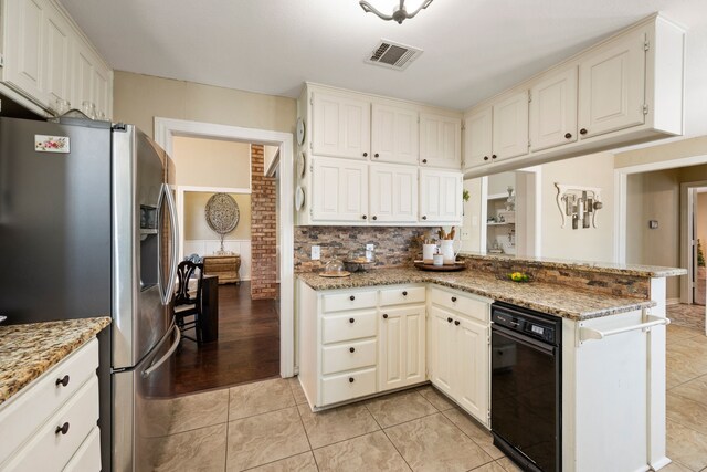 kitchen featuring stainless steel fridge with ice dispenser, tasteful backsplash, light stone counters, and visible vents