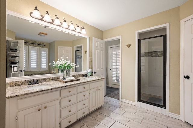bathroom with a sink, tile patterned flooring, a stall shower, and double vanity