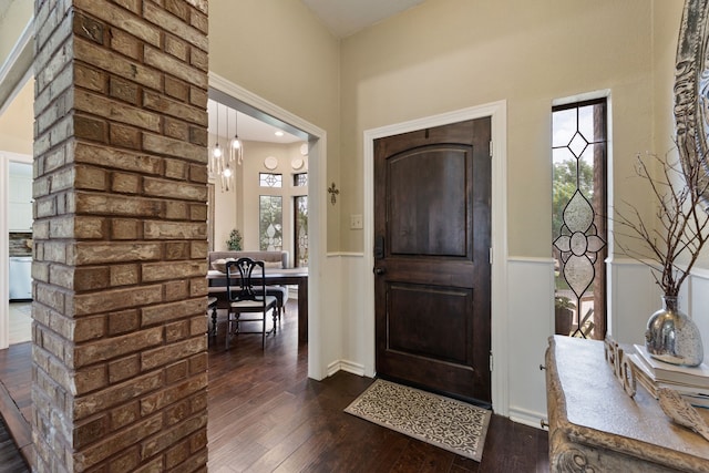 entryway featuring dark wood-type flooring, wainscoting, and a high ceiling