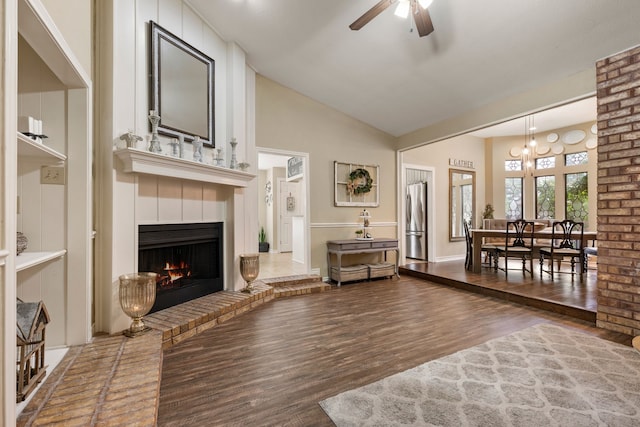 living area with ceiling fan, wood finished floors, a fireplace, and high vaulted ceiling