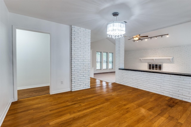 10119 Chisholm Trl, Dallas, TX 75243 - unfurnished living room featuring brick wall, wood finished floors, a chandelier, ceiling fan, and baseboards