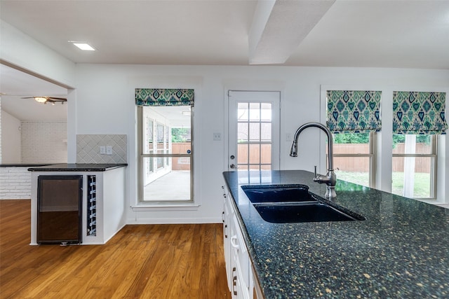 10119 Chisholm Trl, Dallas, TX 75243 - kitchen with a sink, beverage cooler, wood finished floors, white cabinetry, and tasteful backsplash