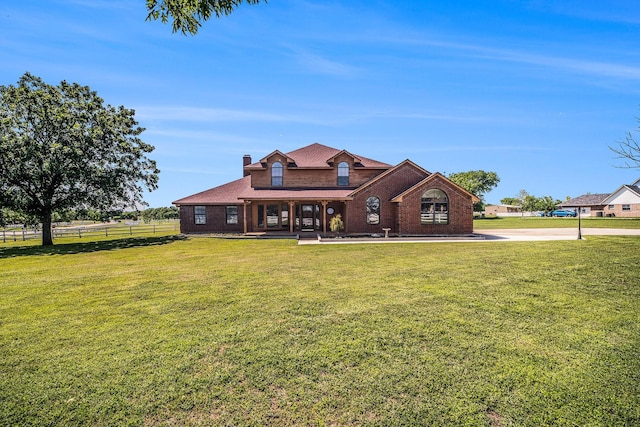 view of front of home with a porch, a chimney, a front yard, brick siding, and fence